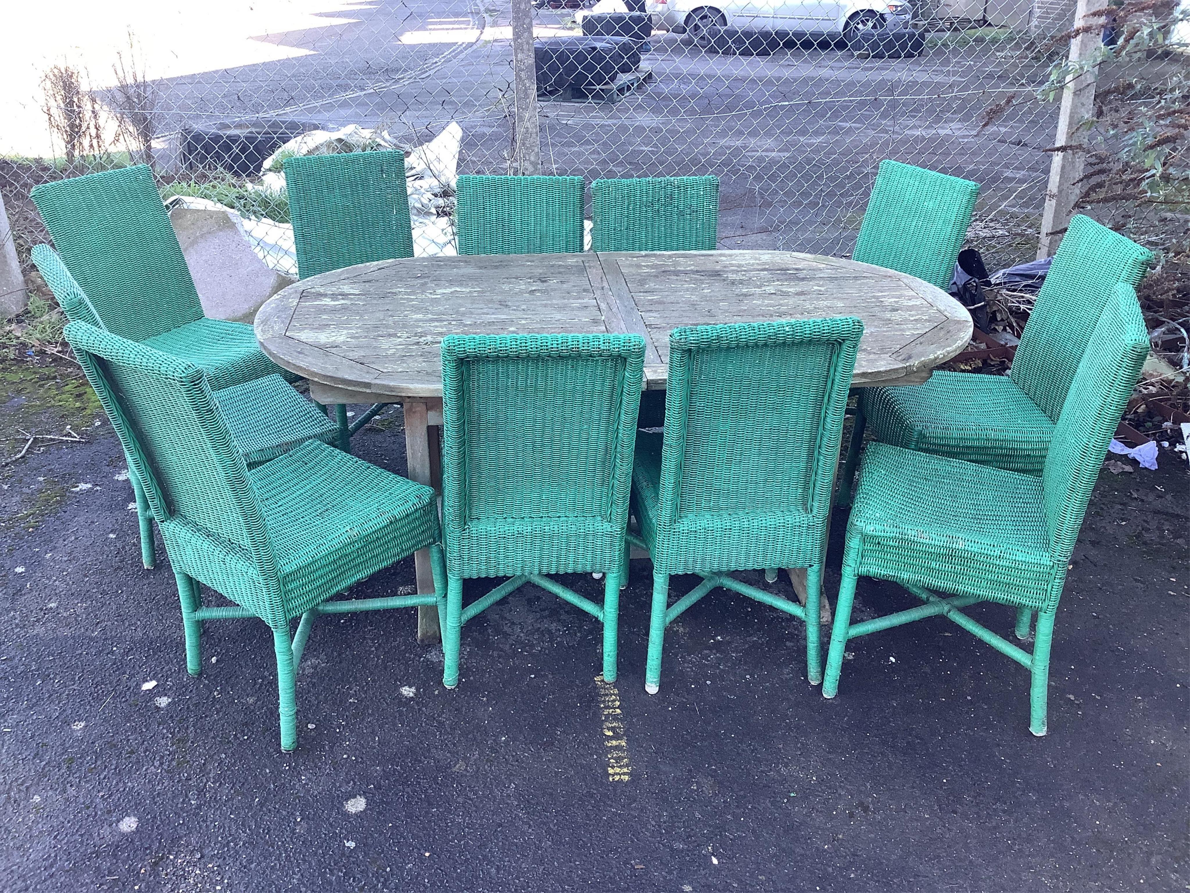 A weathered teak garden table, width 180cm, depth 99cm, height 75cm and eleven Habitat wicker chairs. Condition - poor